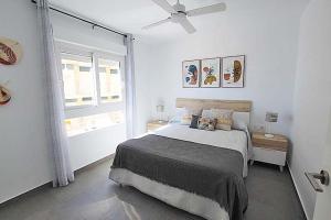 um quarto branco com uma cama e uma janela em Apartamento Primera Línea Playa Centro de Guardamar em Guardamar del Segura