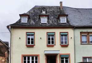 une maison blanche avec des fenêtres et un toit noir dans l'établissement Gästehaus Weingut Schier im historischen Zehnthof, à Reil