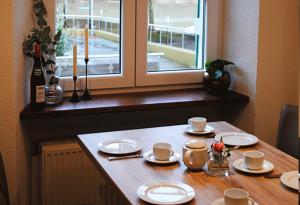 a table with plates and cups and a window at Gästehaus Weingut Schier im historischen Zehnthof in Reil