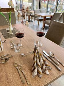 a wooden table with glasses of wine and silverware at Haus Hohenzollern & Haus 'Ambiente in Bad Bertrich