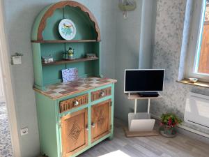 a room with a tv and a desk with a computer at La Maison Bleue in Préveranges