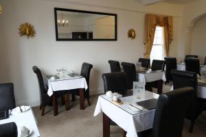 a dining room with tables and chairs and a mirror at The Sandpiper Guest House in Torquay