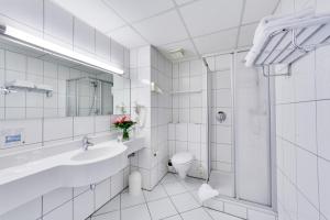 Baño blanco con aseo y ducha en Trans World Hotel Columbus, en Seligenstadt