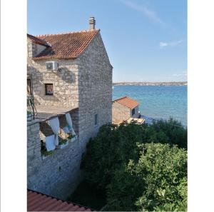 an external view of a stone house with the ocean in the background at Heritage Stone House by the Sea in Prvić Šepurine