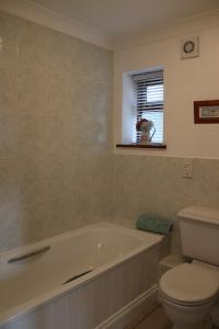 a bathroom with a tub and a toilet and a window at 1 Barge Cottage in Narborough +27 photos