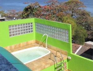 a green building with a bath tub in it at pousada do rei in Pedra de Guaratiba