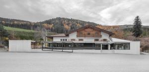 a large white building with a mountain in the background at Hotel Restaurant Putzer in Naz-Sciaves