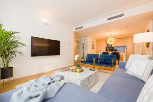 a living room with a blue couch and a tv at Rafael Kaiser - Premium Apartments City Centre - Contactless 24h Check-In in Vienna