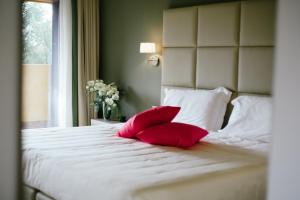 2 cuscini rossi su un letto bianco con finestra di Hotel Villa Borghi a Varano Borghi