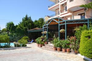 a hotel with potted plants in front of a building at JB Hotel in Sarandë