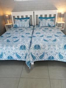 łóżko z niebiesko-białą kołdrą i poduszkami w obiekcie Petite Selfcatering Accommodation Struisbaai SA w mieście Struisbaai