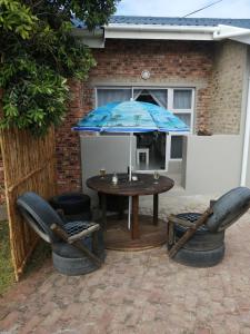 patio ze stołem, krzesłami i parasolem w obiekcie Petite Selfcatering Accommodation Struisbaai SA w mieście Struisbaai