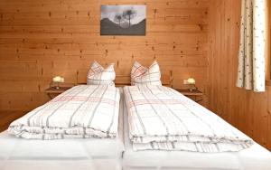 - 2 lits dans une chambre dotée de murs en bois dans l'établissement Schmiedlarhof, à Au im Bregenzerwald