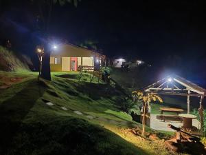 una casa con un banco y una mesa de picnic por la noche en Espaço inteiro: Casa de campo nas montanhas, en Domingos Martins