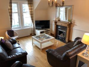een woonkamer met lederen meubels en een open haard bij Oakbank - Comfort in the Glens! in Edzell