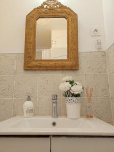 a bathroom sink with a mirror and flowers on it at Casa Flamingo - Appartement calme et moderne - 4 - in Canet-en-Roussillon