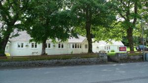 una casa bianca con degli alberi di fronte di Bonnie Lodge by Broadford Hotel a Broadford