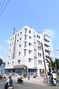 a white building with people riding motorcycles on the street at Hotel Marvic in Tiruchchirāppalli