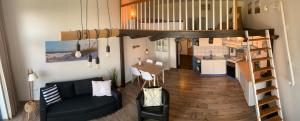 a living room with a couch and a spiral staircase at Ferienwohnung Harlequartier im Wikingerhof direkt an der Harle in Wittmund