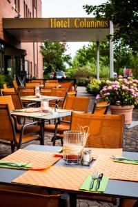 an outdoor restaurant with tables and chairs and a hotel columbus sign at Trans World Hotel Columbus in Seligenstadt