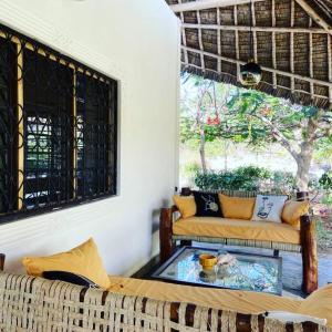 a living room with two couches and a glass table at Villa Isla del Amore in Watamu