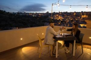 um homem e uma mulher sentados numa mesa com copos de vinho em Fico - Finestra Contemporanea em Ragusa