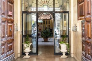 een toegang tot een gebouw met twee vazen bij Hotel Ferrarese in Rome