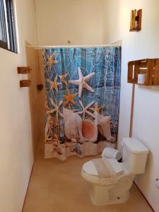 a bathroom with a toilet and a shower curtain at EncantaLuna in Holbox Island