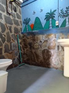 a bathroom with two toilets and a wall with a mural at Camping Trópico de Capricórnio - Ilhabela in Ilhabela