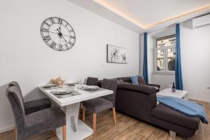 a living room with a table and a couch and a clock at Mary apartment #1 in Rijeka