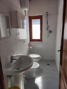 een badkamer met een wastafel, een toilet en een raam bij Agriturismo il fosso in Cutigliano