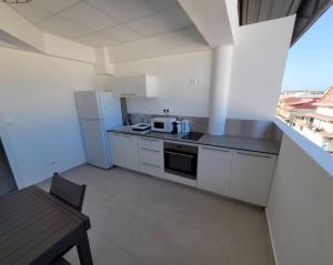a small kitchen with white appliances and a table at Hello Guyane, Suite Collection (5), 5 étoiles. in Cayenne