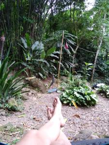 una persona con los pies en un jardín en Camping Trópico de Capricórnio - Ilhabela, en Ilhabela