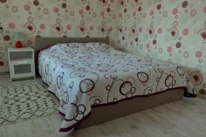 a bedroom with a bed with a white and pink comforter at Estate I Apartamentai in Birštonas