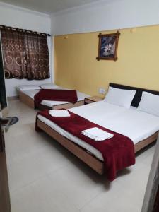 two beds in a hotel room with red blankets at HOTEL S K PALACE in Mahabaleshwar
