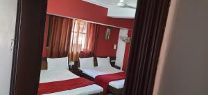 two beds in a room with red walls and a mirror at HOTEL S K PALACE in Mahabaleshwar