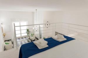 a white room with a bed with blue sheets at Alicam in Uggiano la Chiesa