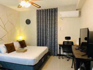 a hotel room with a bed and a desk and a computer at Quayside Condo near Airport in Mactan