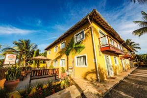 a yellow house with a balcony and palm trees at Pousada Ravenalas - Apartamentos e Flats in Barra Grande