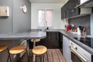 eine Küche mit einer Theke und einigen Hockern in der Unterkunft Duplex cosy et contemporain avec parking privé in Amiens + 4 Fotos