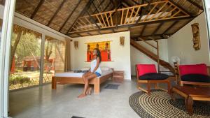 une femme assise sur un lit dans une pièce dans l'établissement KiteParadise-Madagascar, à Diego Suarez