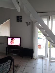 een woonkamer met een televisie en een trap bij Appart cosy Disney paris in Chalifert