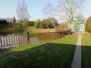 ein Holzzaun in einem Hof mit einem Gewässer in der Unterkunft Détente à la campagne in Cossé-le-Vivien