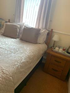 ein Schlafzimmer mit einem Bett, einem Nachttisch und einem Fenster in der Unterkunft The Pines Guest House in Whitley Bay