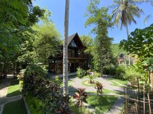 una casa con jardín y palmeras en Comfortable Wood House second floor and attic, en Kuta Lombok