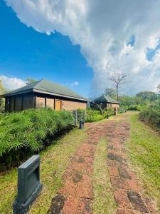 een onverharde weg voor een huis met een gebouw bij The Postcard Hideaway, Netravali Wildlife Sanctuary, Goa in Vichondrem