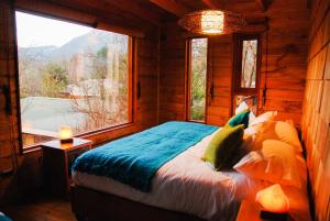 a bedroom with a bed and a large window at Aldea Naukana Posada Boutique in Pucón