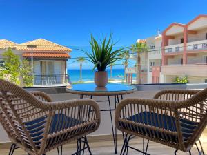 een patio met 2 stoelen en een tafel met een potplant bij Roula Kotsonis Superior Apartment in Argassi