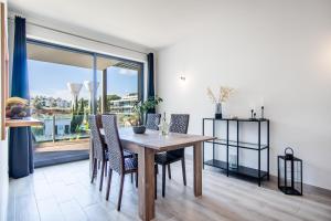 ein Esszimmer mit einem Tisch und Stühlen sowie einem großen Fenster in der Unterkunft Appartement Luxueux dans un site Exceptionnelle Vilamoura in Vilamoura