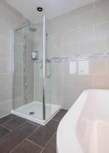a bathroom with a shower and a toilet and a tub at Laundimer House in Corby